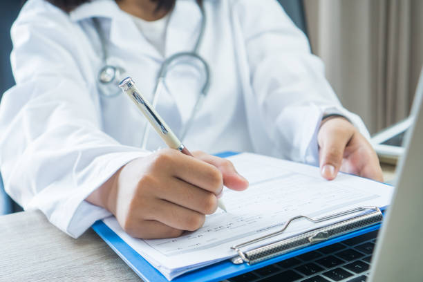 Healthcare medical concept. Woman Doctor writing prescription clipboard with record information paper, working laptop computer in hospital, wearing white gown, Stethoscope on neck for treating patient concepto médico de la salud. mujer doctor escribiendo portapapeles de prescripción con papel de información de registro, computadora portátil de trabajo en el hospital, usando vestido blanco, estetoscopio en el cuello para el tratamiento del paciente