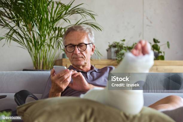 Senior Man With Broken Leg At Home Stock Photo - Download Image Now - Physical Injury, Men, Orthopedic Cast