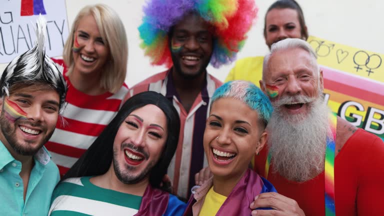 Happy gay people laughing in front of camera at lgbt pride party