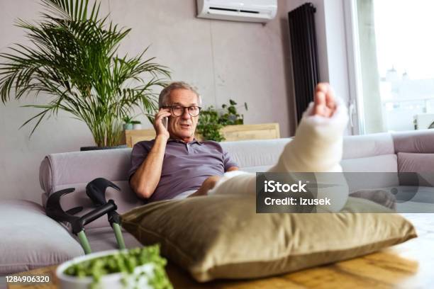 Senior Man With Broken Leg At Home Stock Photo - Download Image Now - Crutch, Orthopedic Cast, Senior Men