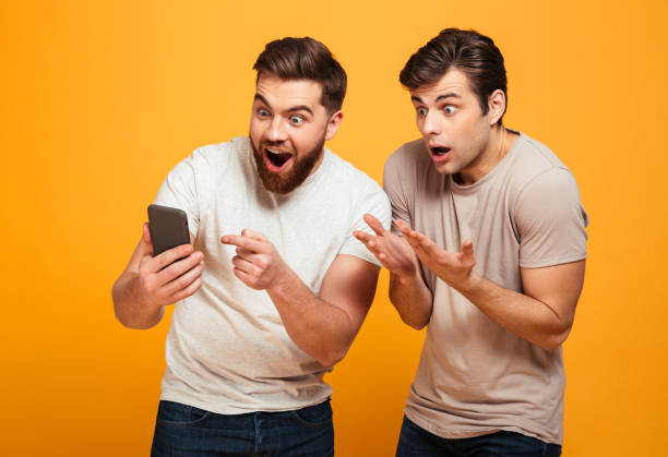 istock Image of two bachelors screaming and gesturing while watching game on mobile phone, isolated over yellow background 1284906479