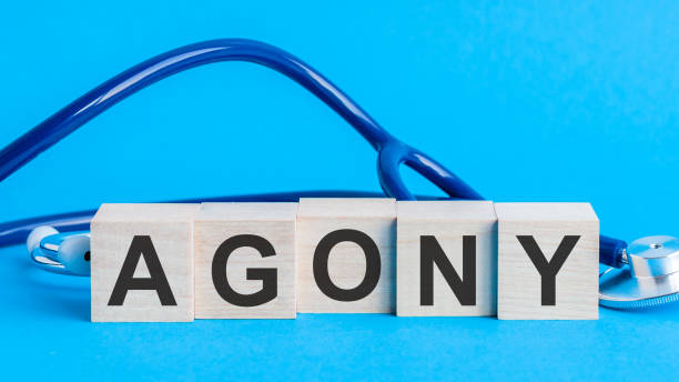 istock Agony word written on wooden blocks and stethoscope on light blue background 1284908296