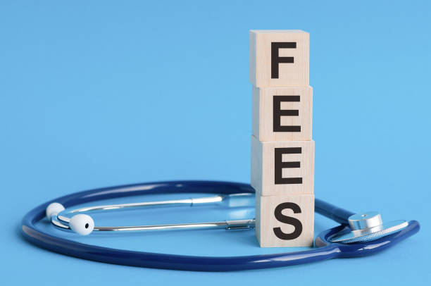 istock fees word written on wooden blocks and stethoscope on light blue background 1284908304