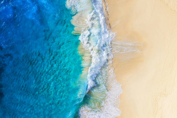 istock Beach and large ocean waves. Coast as a background from top view. Blue water background from drone. Summer seascape from air. Travel image 1284908434