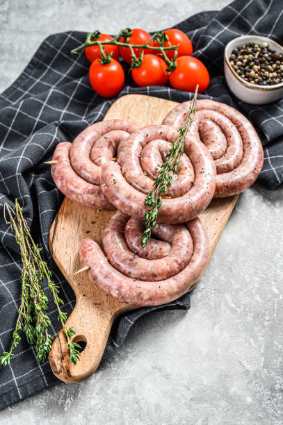 istock Fresh raw spiral chicken sausages. Gray background. Top view 1284908583