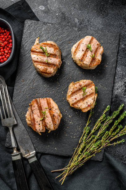istock grilled pork steak tenderloin with fresh herbs. black background. Top view 1284909489