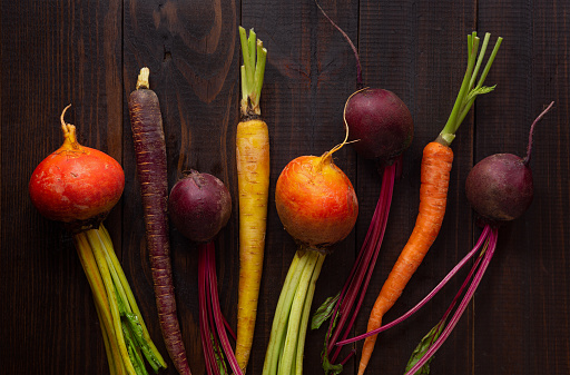 Overhead view of fresh organic yellow and red beets and carrots on a wooden surface