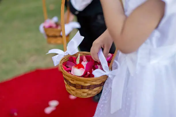 Photo of Flower Girl and boy hands holding flower hanging basket at wedding