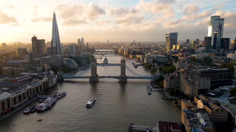 Panoramic aerial view to the modern skyline of London, United Kingdom, along the Thames river with the skyscrapers of the City during sunset time