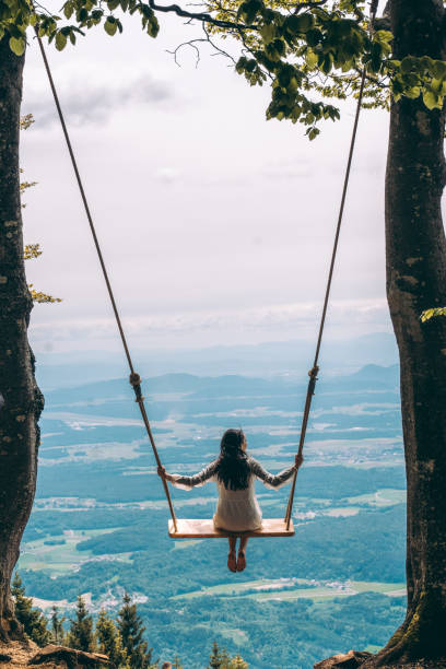 istock Woman sitting on swing in mountains 1284912536
