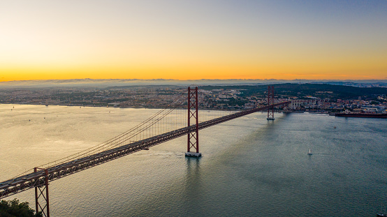 Aerial view shot of the April 25th Bridge and the Tagus River under a moody sky at sunset, Almada, Lisboa Region, Portugal