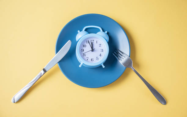 istock Blue alarm clock on an empty blue plate on a yellow background. Top view, copy space 1284914202