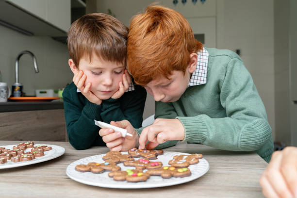 istock Horizontal view of children decorating ginger cookies in the kitchen. 1284914789