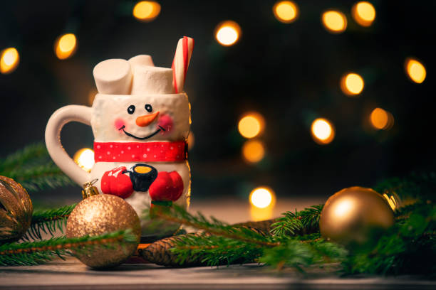A mug shaped like a snowman full of hot chocolate, marshmallows and a peppermint stick.