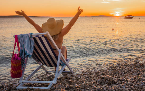 istock Woman in sun hat on deckhair on beach at sunset 1284916377