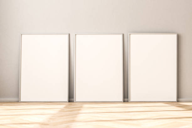 istock Three empty Picture Frames on parquet floor leaning against bright wall. Sunlight flooding in from the left. 3d render mockup. 1284917027