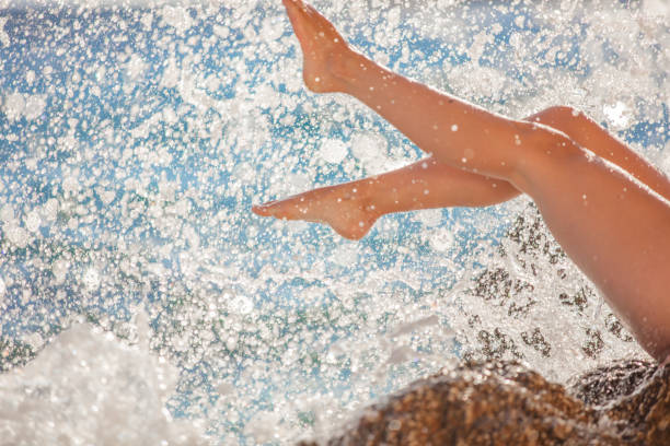Woman sitting on rock and splashing water on sunny summer day