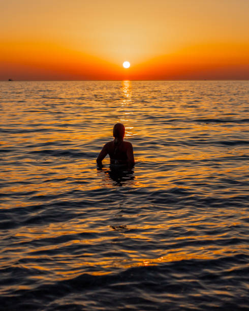 istock Woman relaxing in sea at sunset 1284919446