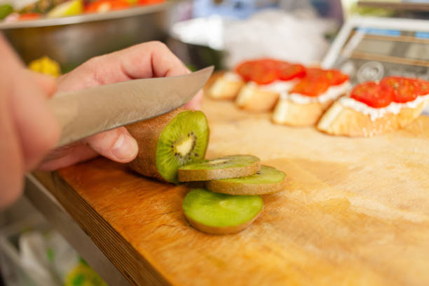 istock A man cuts a kiwi on a wooden board. Natural light 1284919991