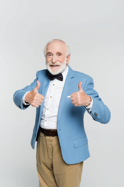 istock Positive senior man showing like gesture and looking at camera isolated on grey 1284921348