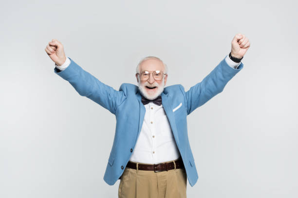 istock Cheerful senior man showing yeah gesture isolated on grey 1284921349