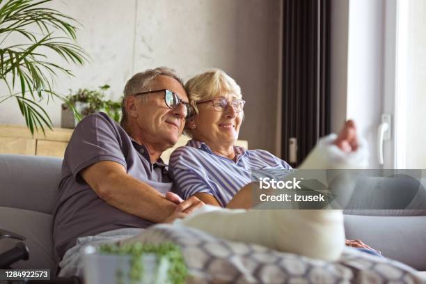 Affectionate Senior Couple At Home Stock Photo - Download Image Now - Broken Leg, Orthopedic Cast, Recovery