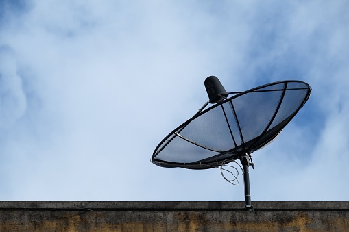 black satellite dish on roof with blue sky