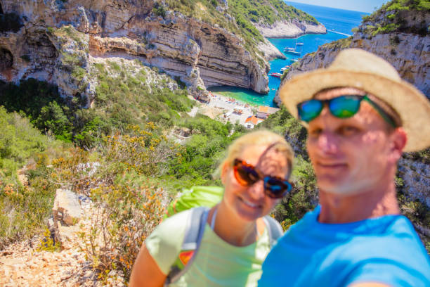 Selfie of a mature tourist couple on a beach with cliffs in the background in the summer