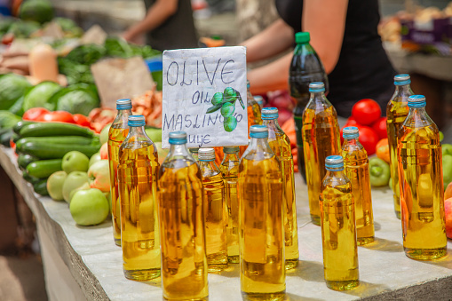 Lots of olive oil in bottles on a market stall in a street