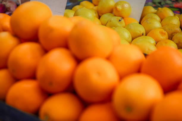 Close-up of a heap of tangerines on a market stall with limes in the background