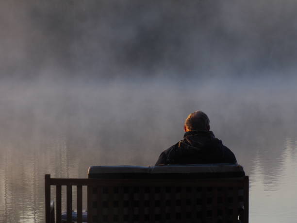 istock Man on bench on a misty morning 1284924874