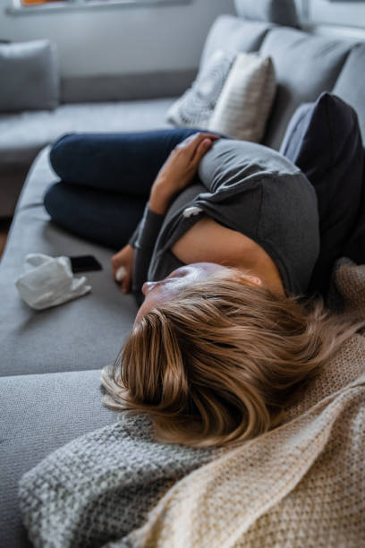 istock Sick woman measuring temperature on the sofa 1284925775