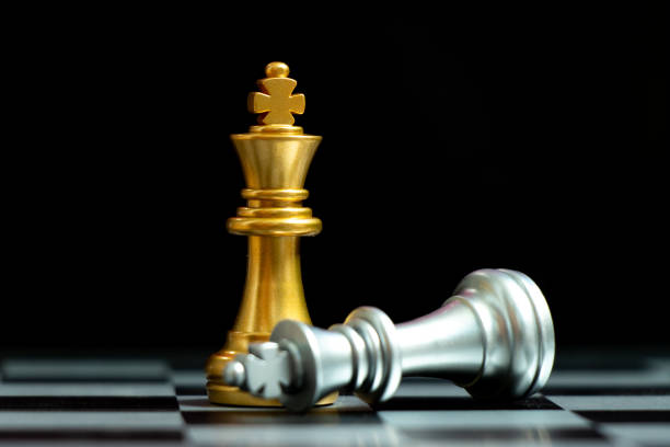 istock Gold king chess piece win over lying down silver king on black background 1284926498