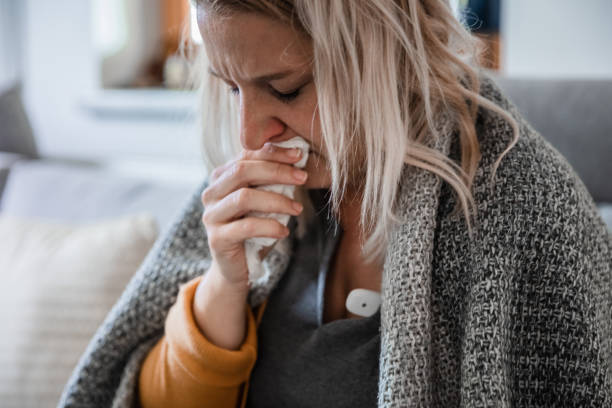 istock A sick woman coughing on the couch at home 1284926534