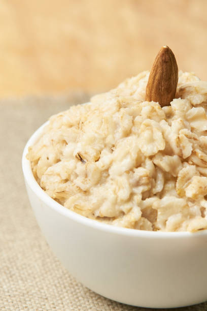 istock White bowl. Oatmeal with almonds and banana. Neutral background 1284927925