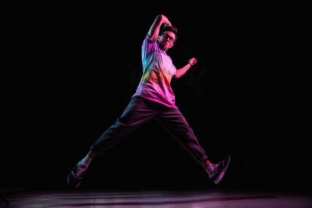 istock Professional break dancer jumping, practicing modern hip-hop dance in pink neon light 1284929325