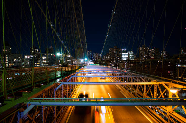 (選択的フォーカス)ニューヨーク市のスカイラインを遠くに乗って夜にブルックリン橋を走行する一部の車の素晴らしい景色。ニューヨーク、マンハッタン、アメリカ合衆国。 - 7603 ストックフォトと画像