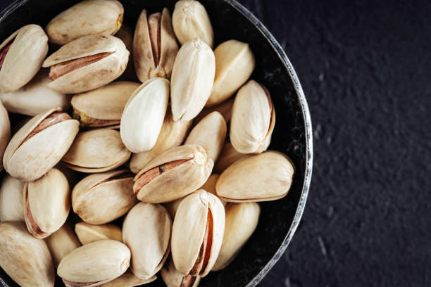 istock Pistachios in steel bowl on dark background. 1284932428