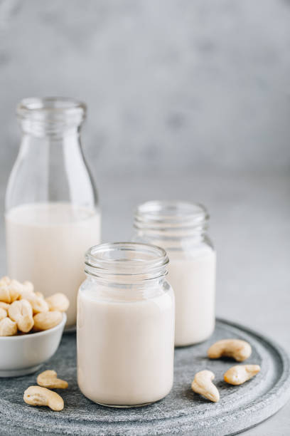 グレーの石の背景にガラスでカシューナッツミルク - cashew apple fruit food jar ストックフォトと画像