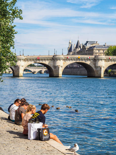 A couple sitting in front of Pont Neuf on Seine River (French Acamedy / Académie Française). stock photo