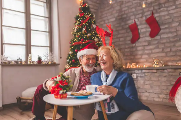 Photo of Senior couple drinking coffee and eating gingerbread cookies on Christmas morning