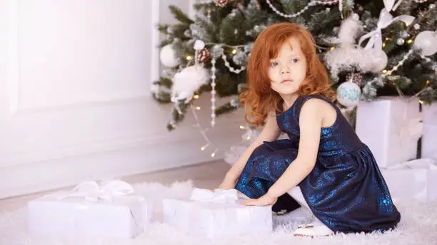 Little girl. White background. Blue dress. New Year xmas child. Christmas eve holiday. interior. gift.