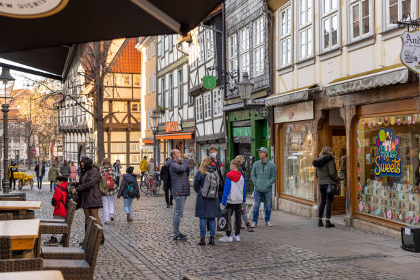 People waiting to get into a candy store in Braunschweig, Lower Saxony Braunschweig, Germany - nov 7th 2020: Amount of people allowed to stores is limited because of coronavirus pandemic. People stand in line outside a candy store waiting to get in. braunschweig stock pictures, royalty-free photos & images