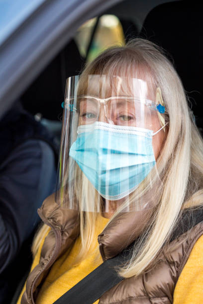 istock Senior couple in car wearing face shield and protective mask 1284937736