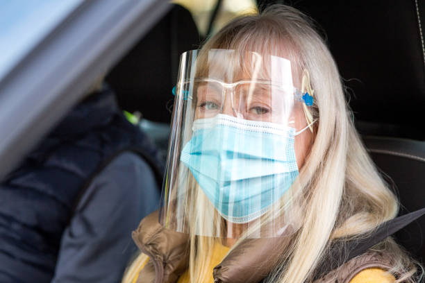 istock Senior couple in car wearing face shield and protective mask 1284937776