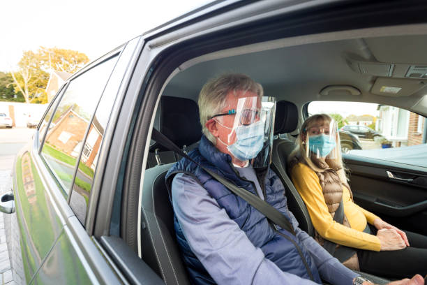 istock Senior couple in car wearing face shield and protective mask 1284937833