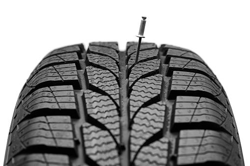 Nail on a car tire isolated on white background