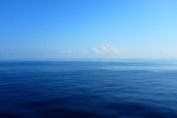 Tranquil scene on open ocean with calm seas Beautiful calm seas out in the open ocean with just a few puffy white clouds on the horizon sea stock pictures, royalty-free photos & images