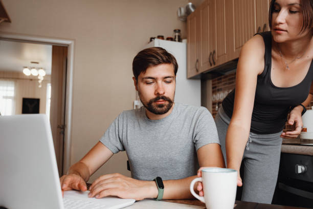 istock Couple at kitchen, reading news and using laptop. 1284942379