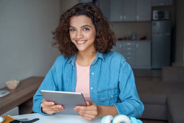 istock Hispanic young woman using tablet and looking at camera. 1284944588